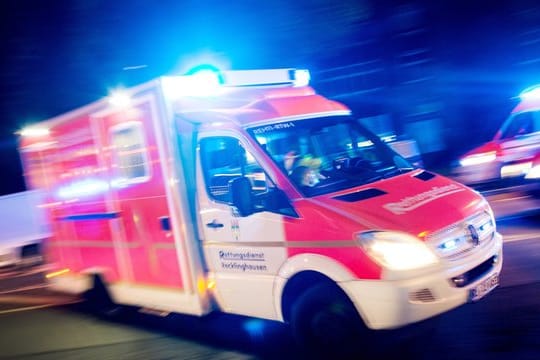 Ein Rettungswagen fährt mit Blaulicht durch eine Straße.