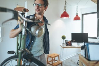 Ein Mann trägt sein Rad in die Wohnung: Ist das Abstellen von Fahrrädern in der Mietswohnung erlaubt?
