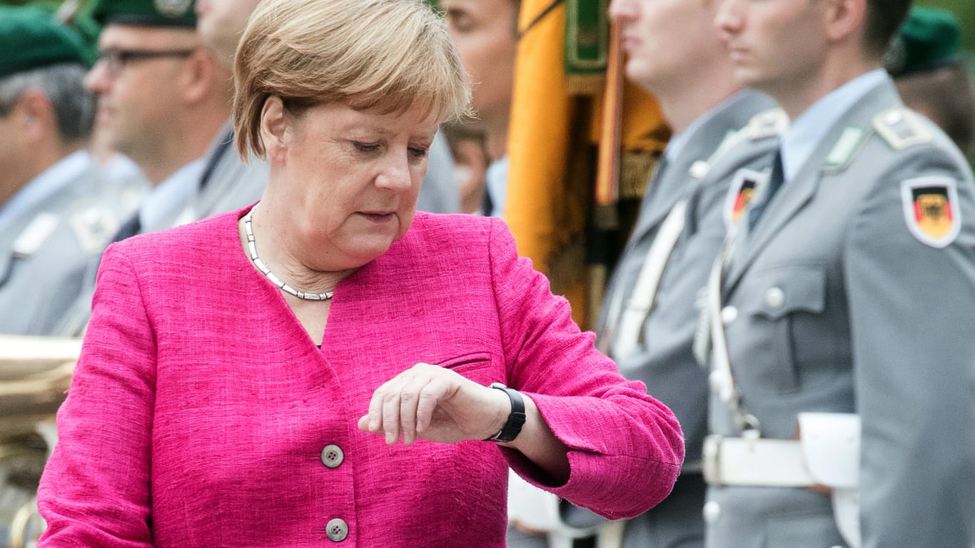 Angela Merkel wirft einen Blick auf die Uhr: Die Abschaffung der Zeitumstellung stößt auch bei der Kanzlerin auf Zustimmung.