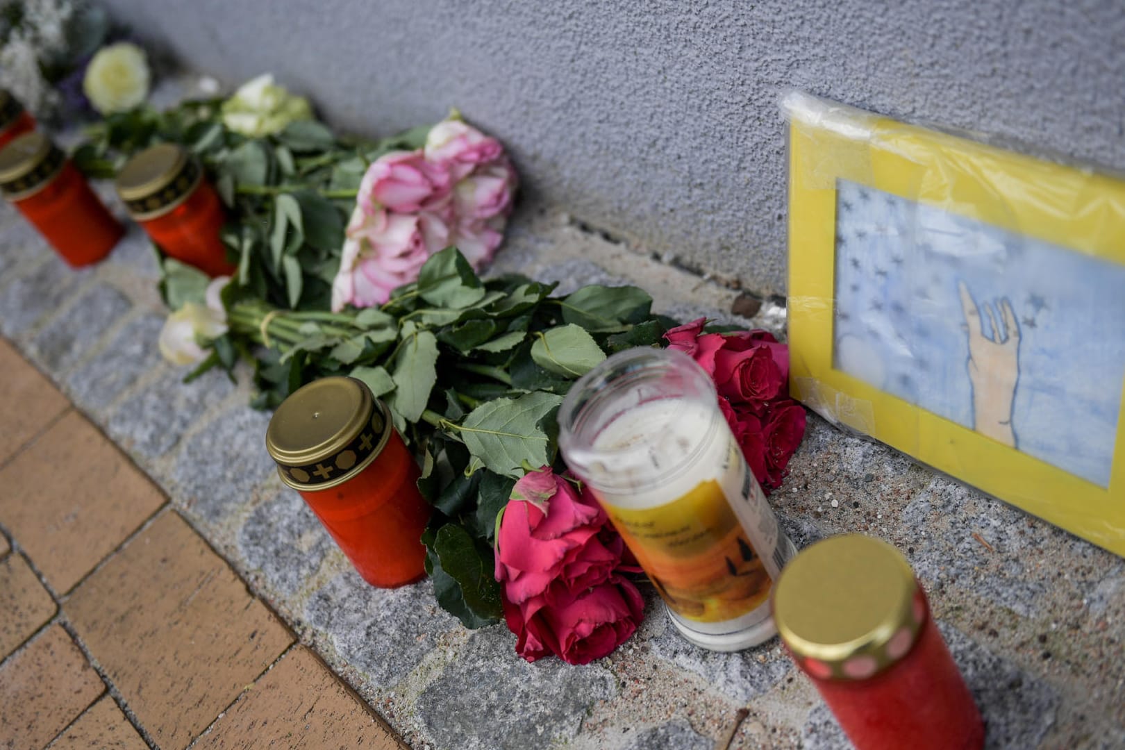 Blumenkränze und Grabkerzen liegen vor einem Haus in dem die 17-Jährige getötet wurde. Das aus Afghanistan stammende Flüchtling soll die Teenagerin aus Eifersucht ermordet haben, glaubt die Staatsanwaltschaft.