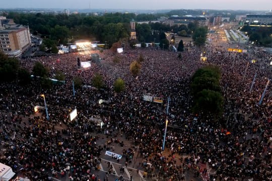 Zuschauer stehen während des Konzerts unter dem Motto "#wirsindmehr" auf dem Parkplatz vor der Johanniskirche.