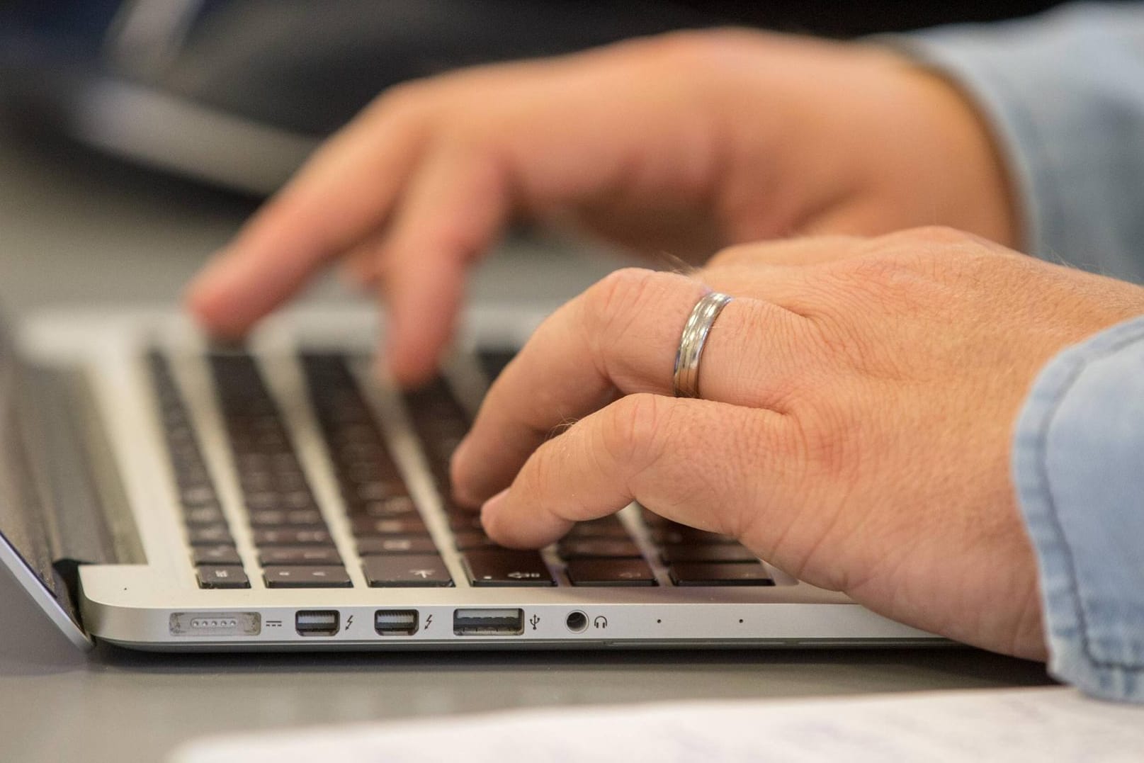 Ein Mann tippt auf einer Macbook-Tastatur: Nützliche Funktionen erleichtern MacOS-Nutzern die Arbeit.