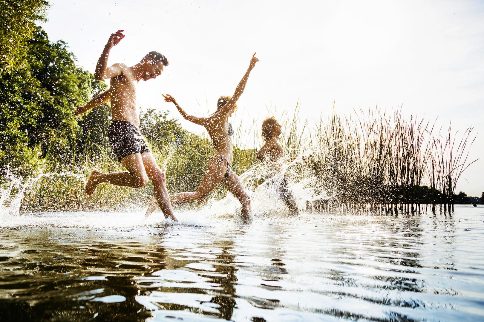 Freunde laufen gemeinsam in einen See.