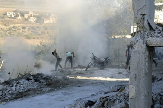 Syrer versuchen einen Brand nach einem Luftangriff im Bezirk Jisr al-Shughur in der Provinz Idlib zu löschen.