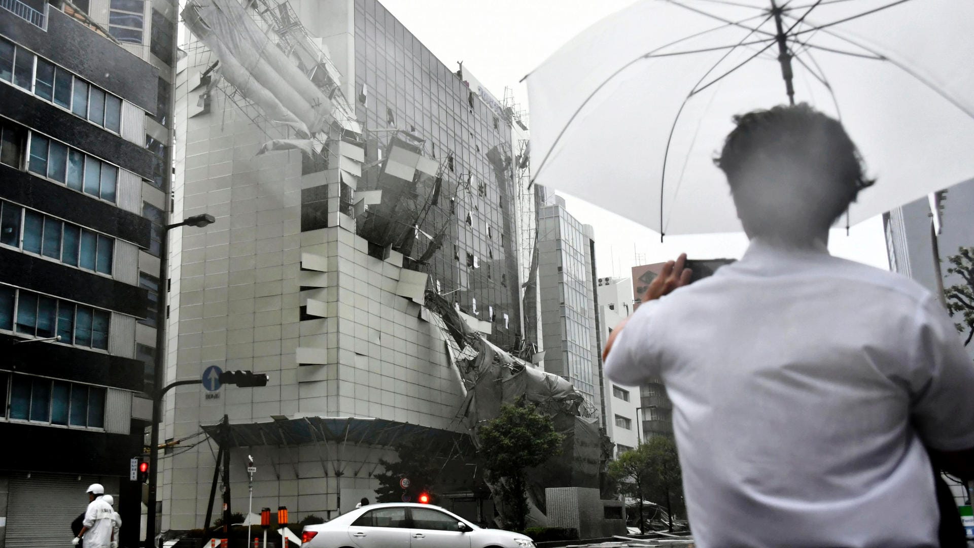 Ein Passant beobachtet das einstürzende Baugerüst eines Gebäudes: Ein Taifun hat Japan schwer verwüstet. Zahlreiche Menschen sollen sich durch umherfliegende Trümmerteile Verletzungen zugezogen haben. Ein Passant beobachtet das einstürzende Baugerüst eines Gebäudes: Ein Taifun hat Japan schwer verwüstet. Zahlreiche Menschen sollen sich durch umherfliegende Trümmerteile Verletzungen zugezogen haben.