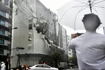 Ein Passant beobachtet das einstürzende Baugerüst eines Gebäudes: Ein Taifun hat Japan schwer verwüstet. Zahlreiche Menschen sollen sich durch umherfliegende Trümmerteile Verletzungen zugezogen haben.