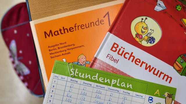 Bücher und ein Stundenplan auf der Schulbank eines Erstklässlers. Bücher und ein Stundenplan auf der Schulbank eines Erstklässlers.