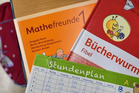 Bücher und ein Stundenplan auf der Schulbank eines Erstklässlers.