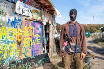 Ein vermummter Umweltaktivist mit einer Gumminase steht in einem Camp von Umweltaktivisten am Hambacher Forst.