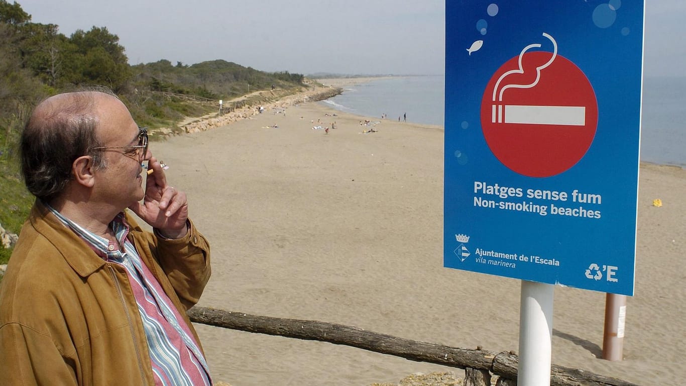 Ein Mann raucht vor einem "Nichtraucher-Strände"-Schild: Derzeit werden Rufe nach rauchfreien Stränden immer lauter, um speziell Familien mit Kindern während der Ferien ein Ambiente ohne Rauch und Zigarettenstummeln zu garantieren.