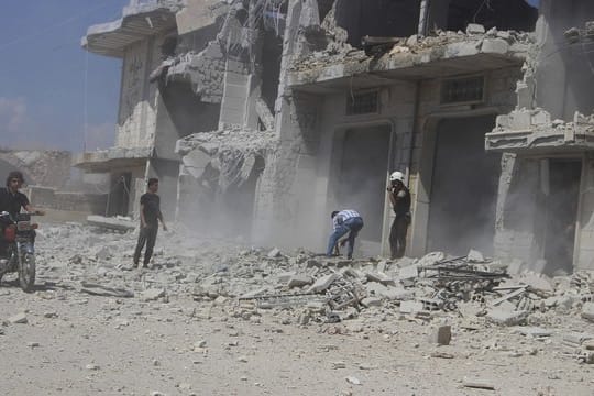 Zivilisten und Zivilschutzarbeiter neben einem Gebäude in Hobeit bei Idlib, das durch einen Luftangriff der syrischen Regierung zerstört wurde.