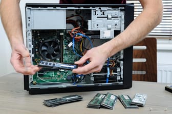 Ein Mann steckt einen RAM-Riegel in einen PC: Langsame Rechner lassen sich unter Umständen mit zusätzlichem Arbeitsspeicher aufrüsten.