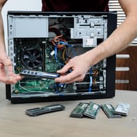 Ein Mann steckt einen RAM-Riegel in einen PC: Langsame Rechner lassen sich unter Umständen mit zusätzlichem Arbeitsspeicher aufrüsten.