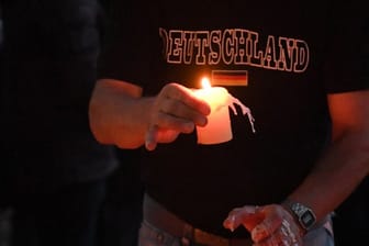 Ein Teilnehmer einer Kundgebung für den verstorbenen 22-Jährigen legt auf einem Spielplatz in Köthen eine Kerze ab.