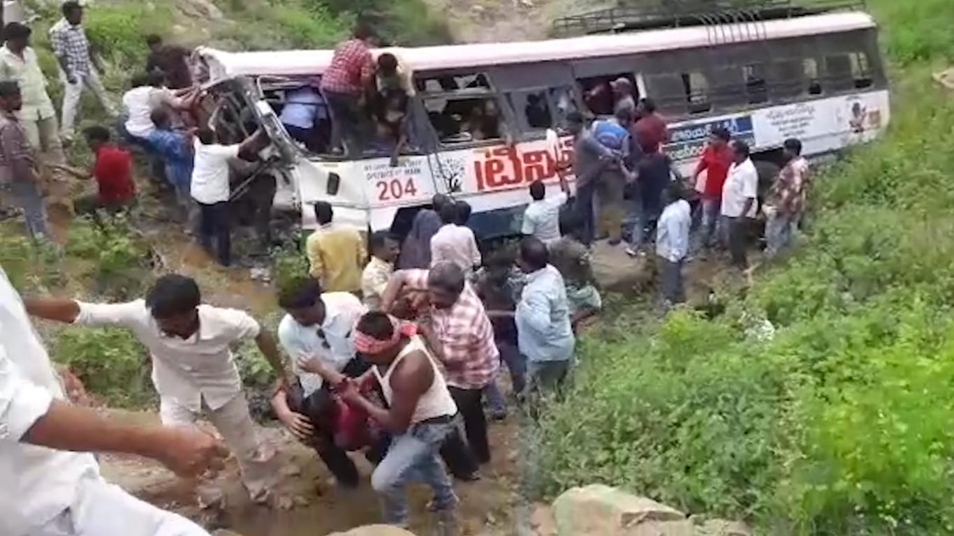 Rettungskräfte ziehen Passagiere aus einem verunglückten Bus: In Indien sind bei dem Busunglück mindestens 49 Menschen gestorben.