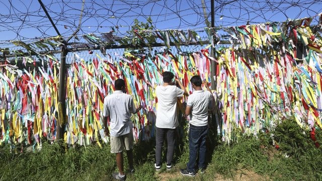 Menschen hängen Spruchbänder mit dem Wunsch zur Wiedervereinigung zwischen Nord- und Südkorea nahe der Grenze zu Nordkorea auf. Menschen hängen Spruchbänder mit dem Wunsch zur Wiedervereinigung zwischen Nord- und Südkorea nahe der Grenze zu Nordkorea auf.