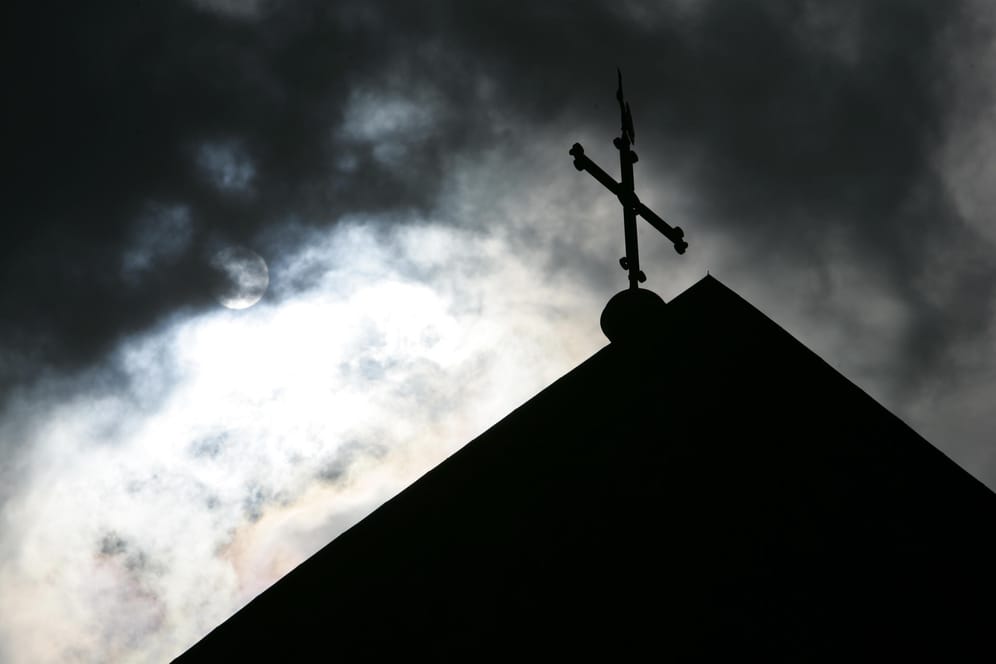 Eine Kirchturmspitze vor einem wolkenverhangenen Himmel (Symbolbild): Eine Studie dokumentiert Missbrauch in der katholischen Kirche in Deutschland.