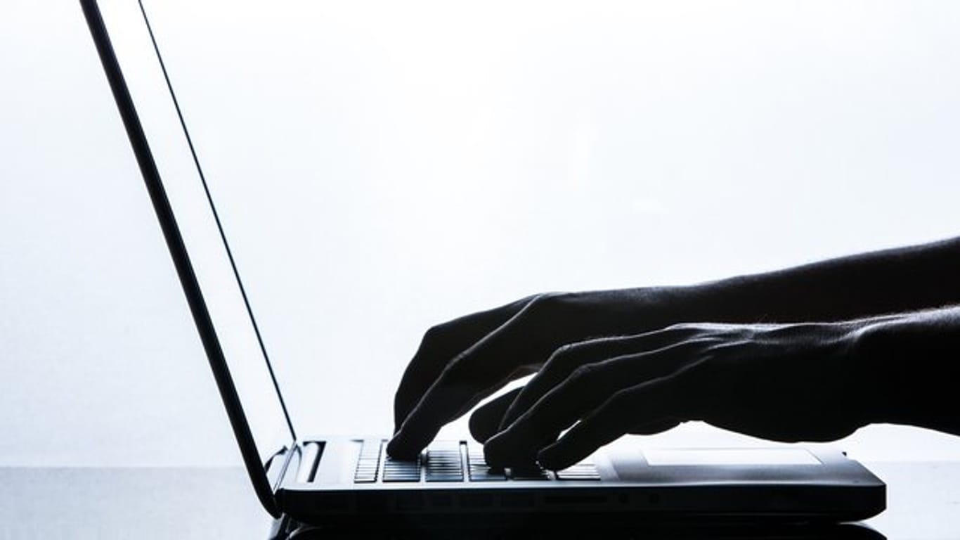 Ein Mann tippt auf der Tastatur eines Laptops.