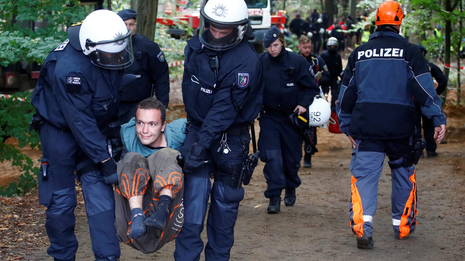 Zwei Polizisten tragen einen Aktivisten davon.