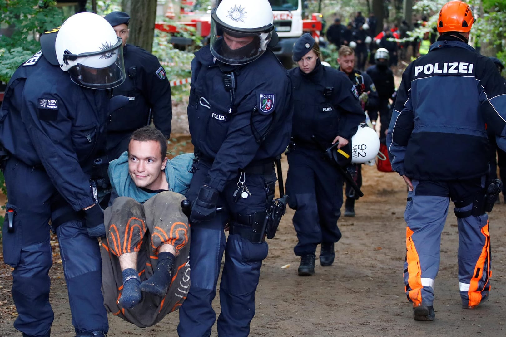 Zwei Polizisten tragen einen Aktivisten davon.