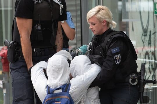 Polizeibeamte tragen einen Demonstranten aus der Landesvertretung von Nordrhein-Westfalen.