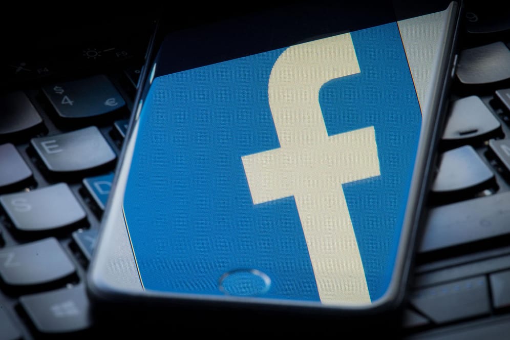 Das Facebook-Logo spiegelt sich auf einem Smartphone-Bildschirm: Das Netzwerk will künftig auch Videos und Bilder einem Faktencheck unterziehen.