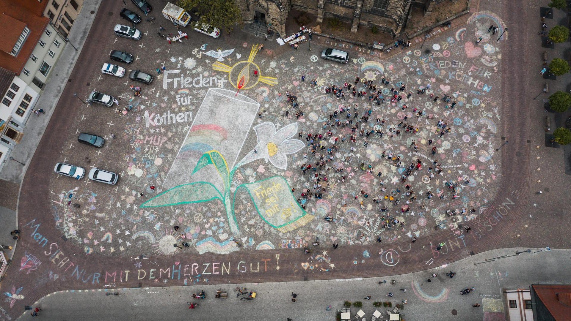 Eine große brennende Kerze wurde auf das Pflaster des Marktplatzes gemalt, umrahmt von einer Blume und einer Friedenstaube. Vor einer geplanten Demonstration mehrerer rechtsgerichteter Gruppierungen haben die Menschen im sachsen-anhaltischen Köthen ihren Marktplatz bunt angemalt.