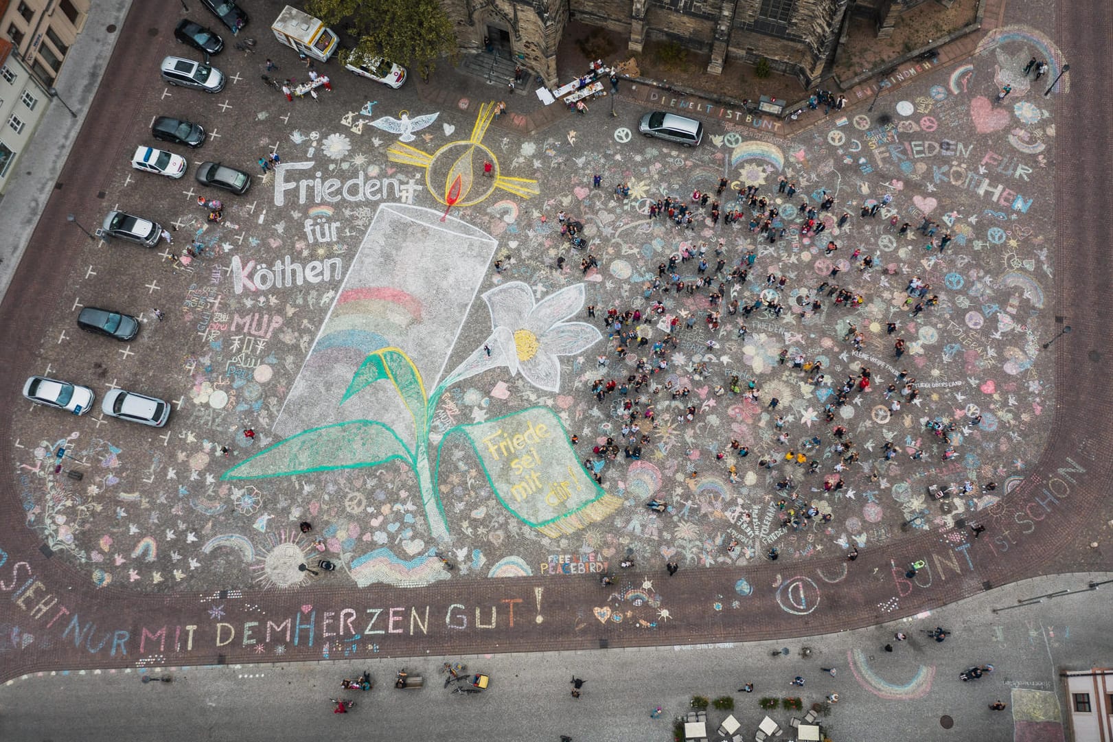 Eine große brennende Kerze wurde auf das Pflaster des Marktplatzes gemalt, umrahmt von einer Blume und einer Friedenstaube. Vor einer geplanten Demonstration mehrerer rechtsgerichteter Gruppierungen haben die Menschen im sachsen-anhaltischen Köthen ihren Marktplatz bunt angemalt.