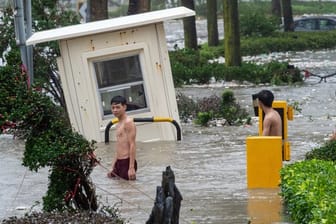 Jugendliche waten durch eine überflutete Straße in Hongkong.
