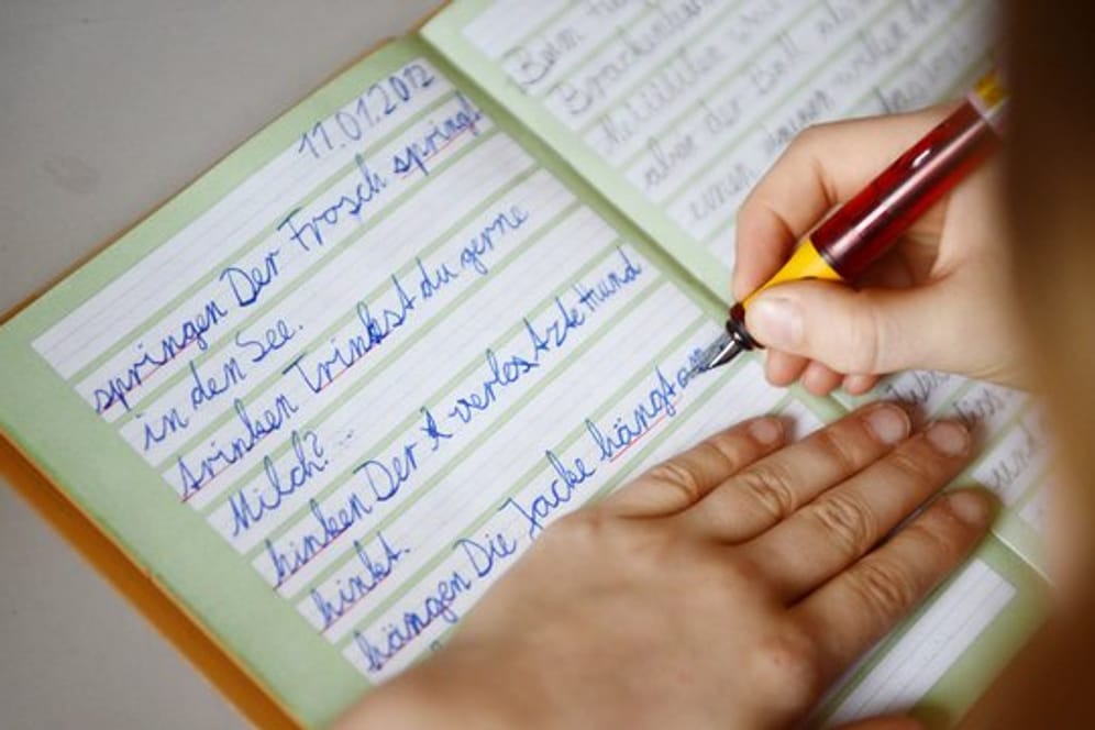 Ein Mädchen übt in ihrem Schreibheft die deutsche Rechtschreibung.