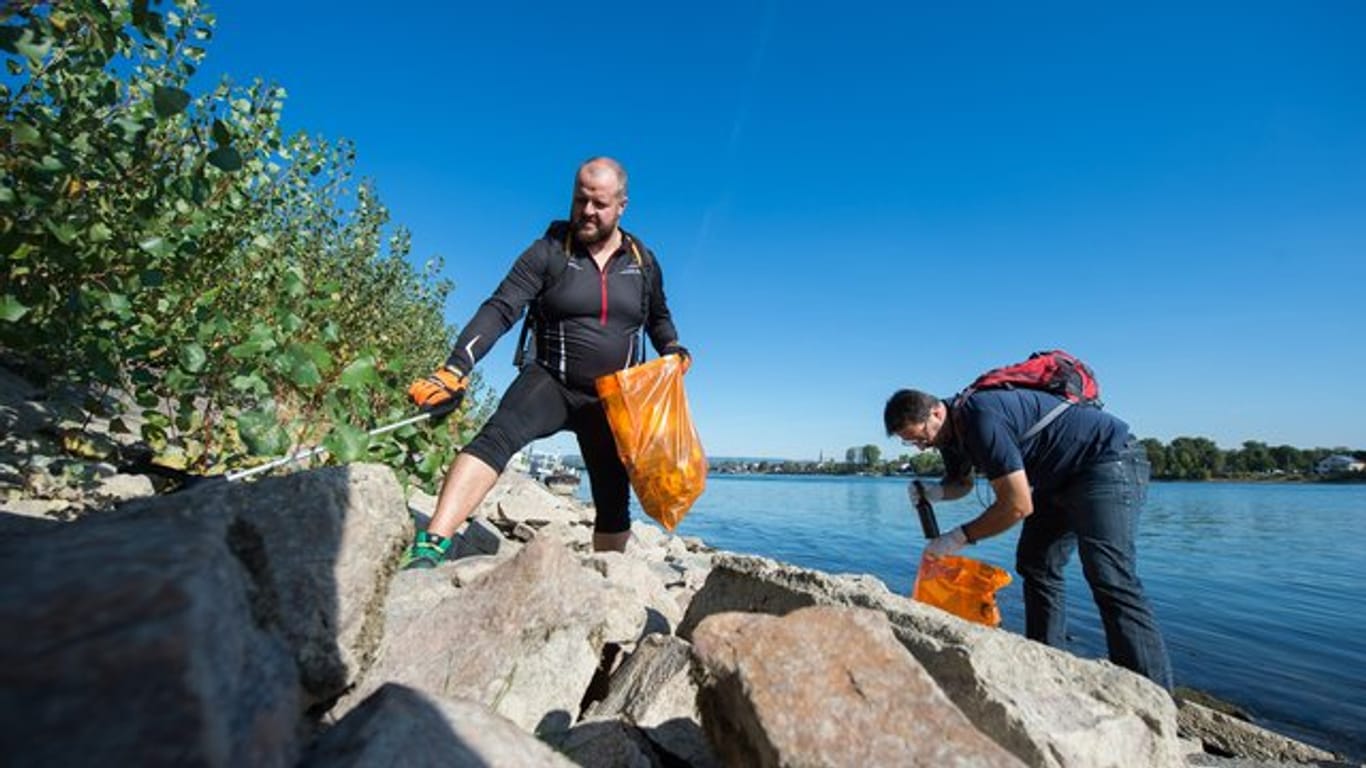 Ehrenamtliche sammeln Müll am Rheinufer in Mainz.
