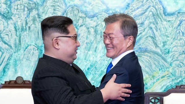 Kim Jong Un (l) und Moon Jae In umarmen sich.