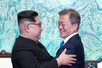 Kim Jong Un (l) und Moon Jae In umarmen sich.
