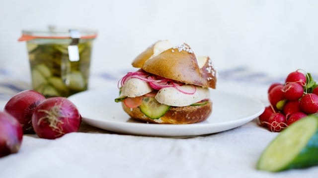 Weißwurstfrühstück mal anders: Hier im Laugenbrötchen mit eingelegtem Gemüse.