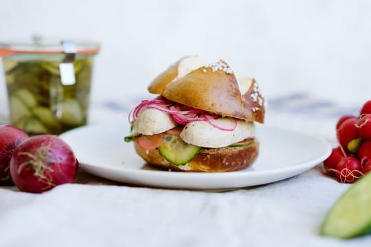 Weißwurstfrühstück mal anders: Hier im Laugenbrötchen mit eingelegtem Gemüse.