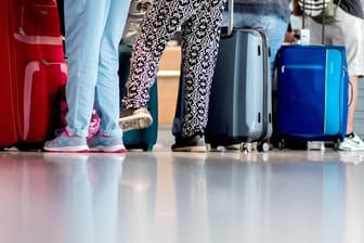 Passagiere stehen mit Gepäck am Flughafen.