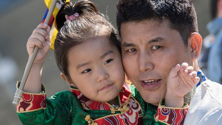 Traditionelle Trachten tragen dieser Tibeter und seine Tochter, die auf die Ankunft des Dalai Lama warten.