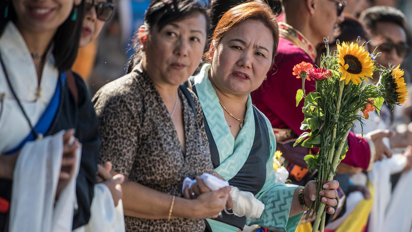 Darmstadt: Mit Sonnenblumen in der Hand wartet eine Frau auf die Ankunft des Dalai Lama.