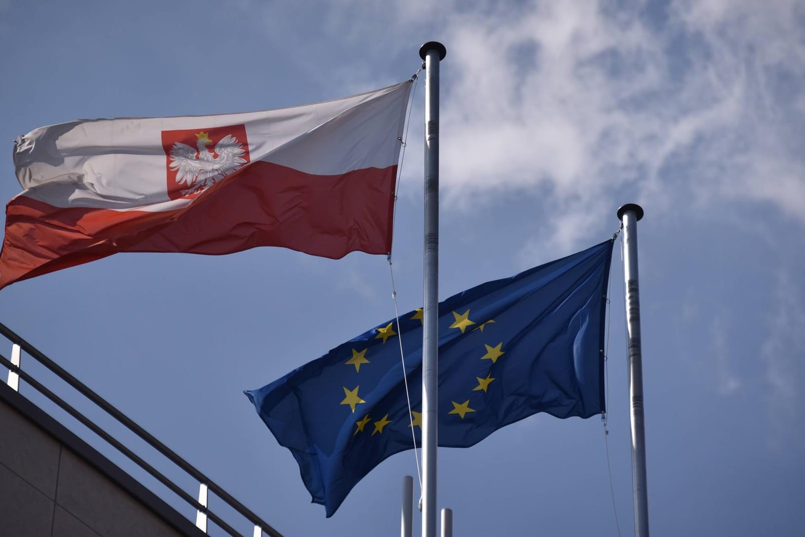 Eine Europa- und eine polnische Flagge auf einem Gebäude: Deutschland und Frankreich wollen am Strafverfahren gegen Polen festhalten. Osteuropäische Länder sehen das kritisch.