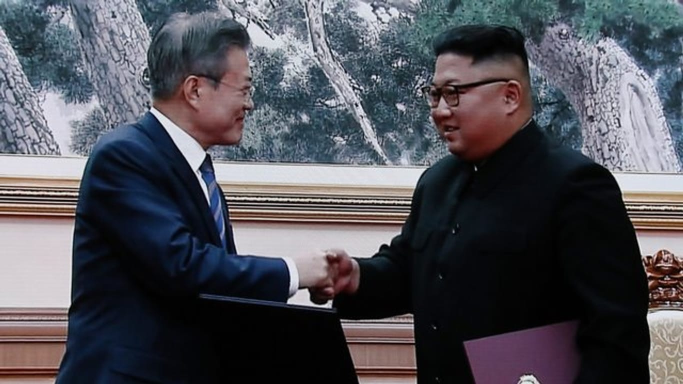 Moon Jae In und Kim Jong Un geben sich nach der Unterzeichnung der Dokumente die Hand.