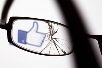 Der Facebook-Daumen ist durch eine kaputte Brille zu sehen: In den USA droht dem sozialen Netzwerk eine Klage wegen diskriminierender Werbepraktiken.