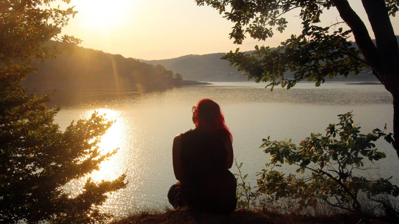 Frau sitzt allein am Ufer des Edersee