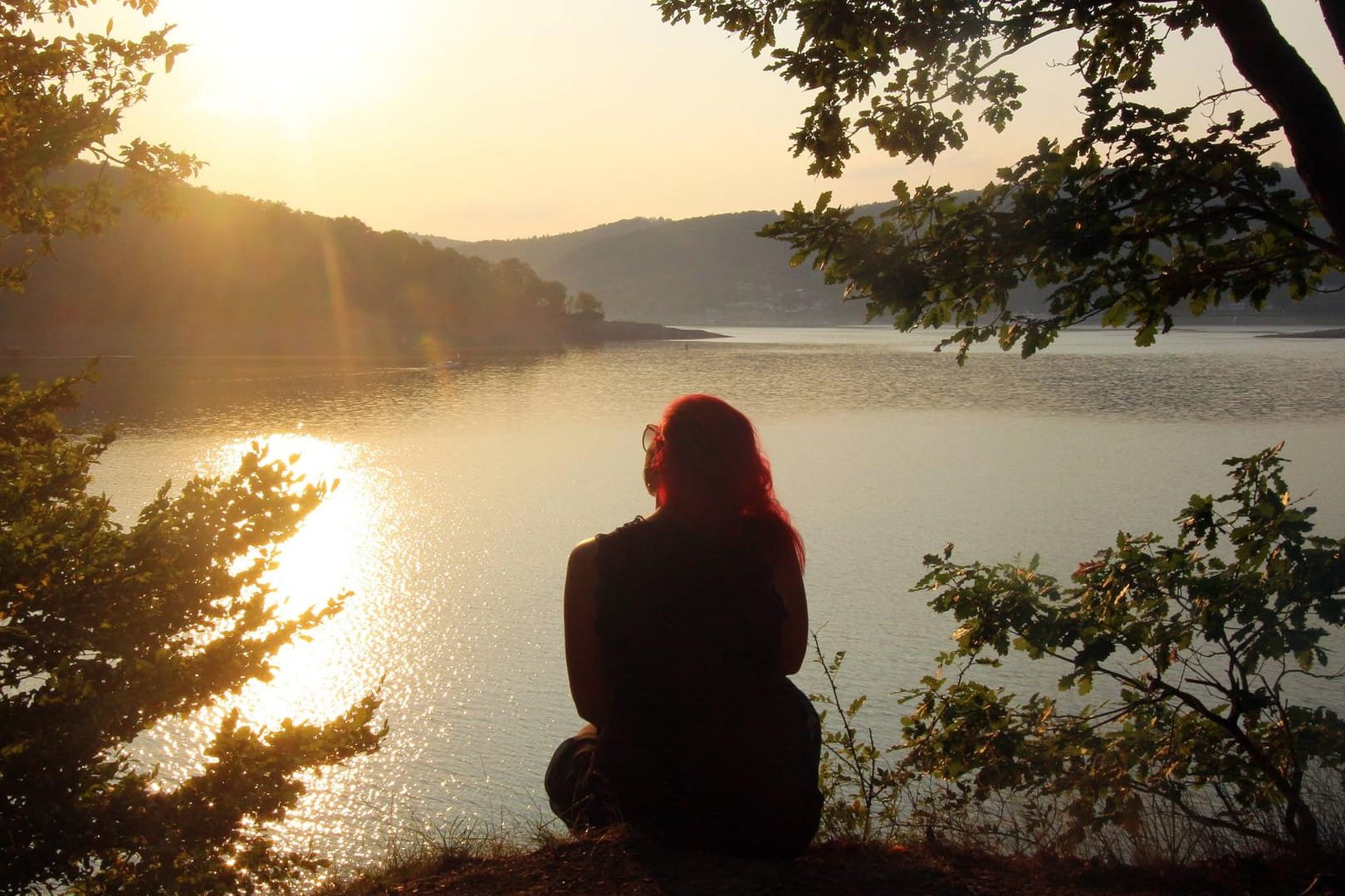 Frau sitzt allein am Ufer des Edersee