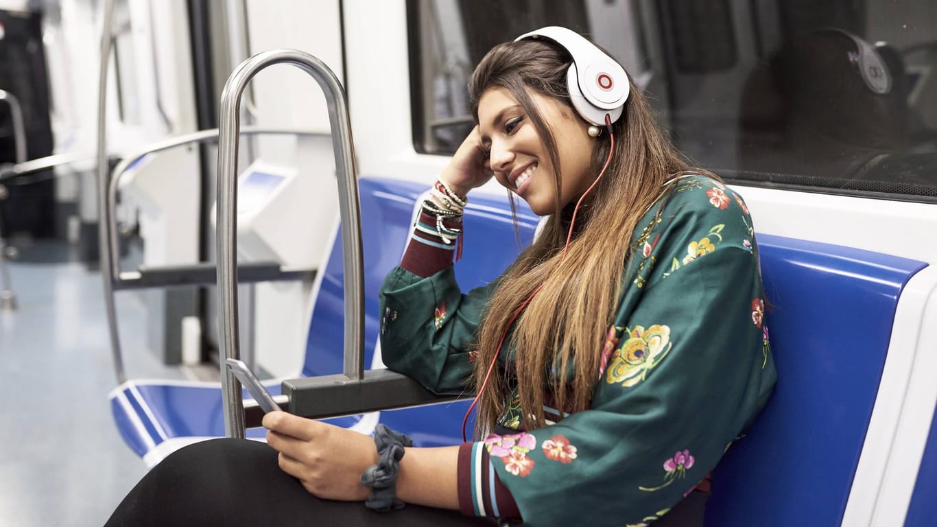Junge Frau mit Kopfhörern in der U-Bahn: Jeder Zweite nutzt Musik-Streaming-Angebote.