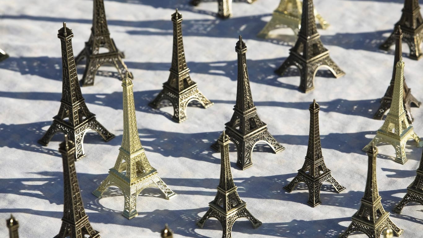 Ansammlung von kleinen Eiffeltürmen auf dem Boden: Das Pariser Wahrzeichen gibt es in Miniaturform an vielen Ecken der Stadt zu kaufen.
