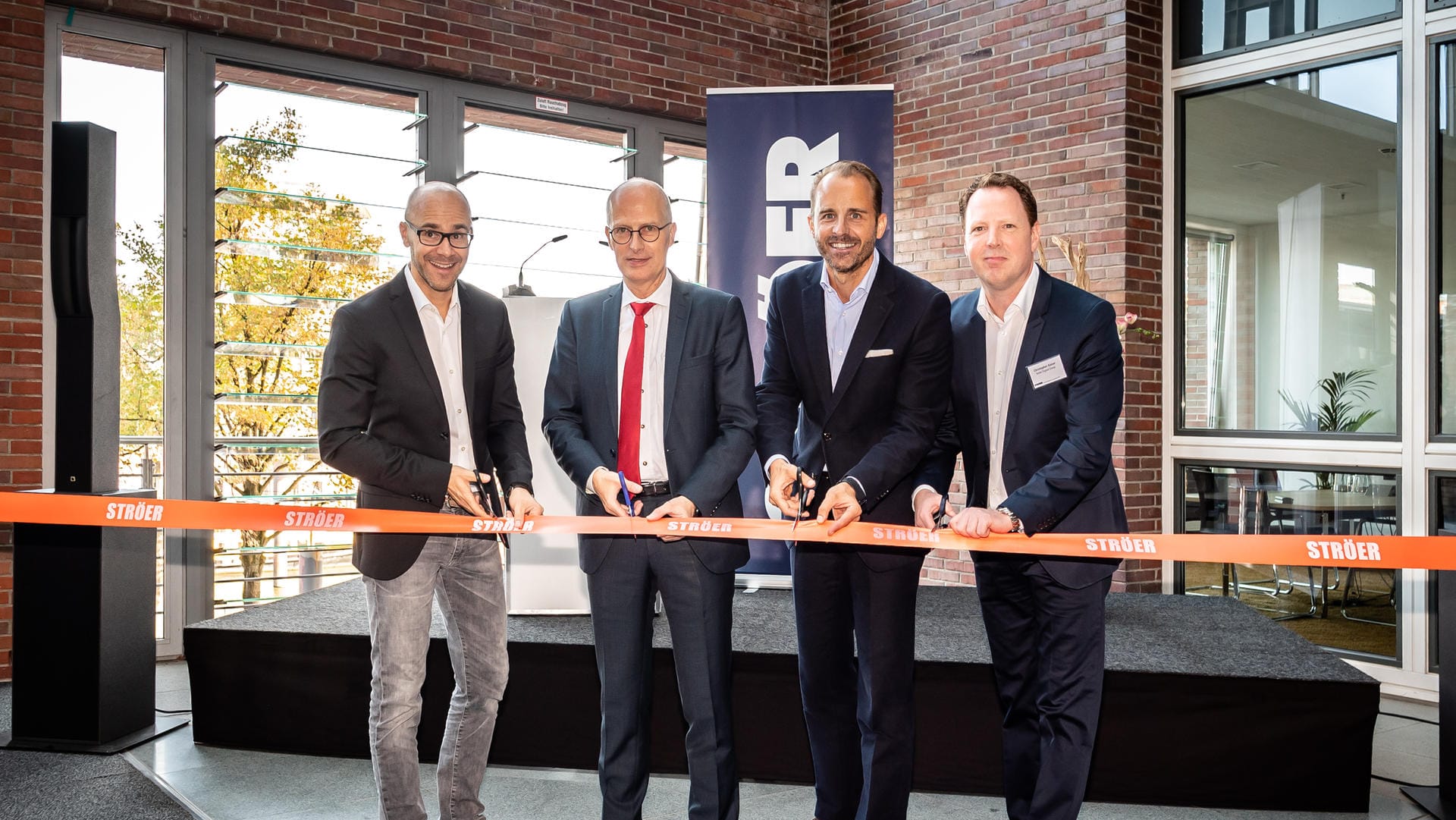Christian Schmalzl (Ströer), Hamburgs Erster Bürgermeister Peter Tschentscher, Alexander Stotz (Ströer) und Christopher Kaiser (Ströer) bei der Eröffnung des Multi-Channel-Hauses in der Hafencity.