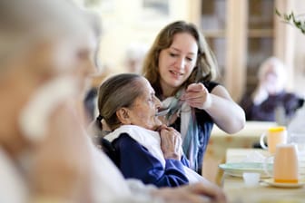 Pflegerin hilft Frau beim Essen: Ist mehr Arbeitszeit eine Lösung für den Pflegenotstand?