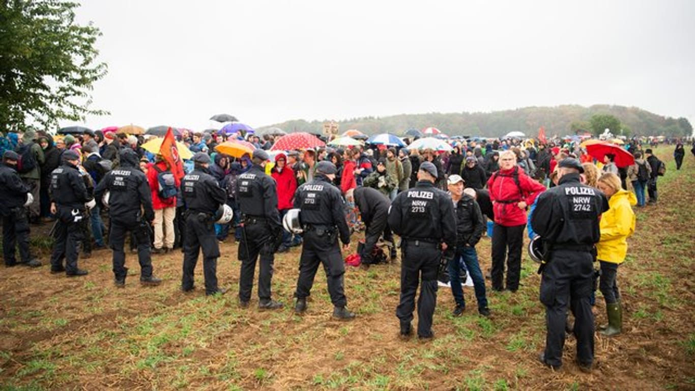 Teilnehmer der Demonstration gegen die Rodung des Hambacher Forsts warten im Regen vor einer Polizeikette.