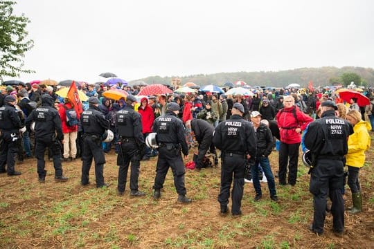 Teilnehmer der Demonstration gegen die Rodung des Hambacher Forsts warten im Regen vor einer Polizeikette.