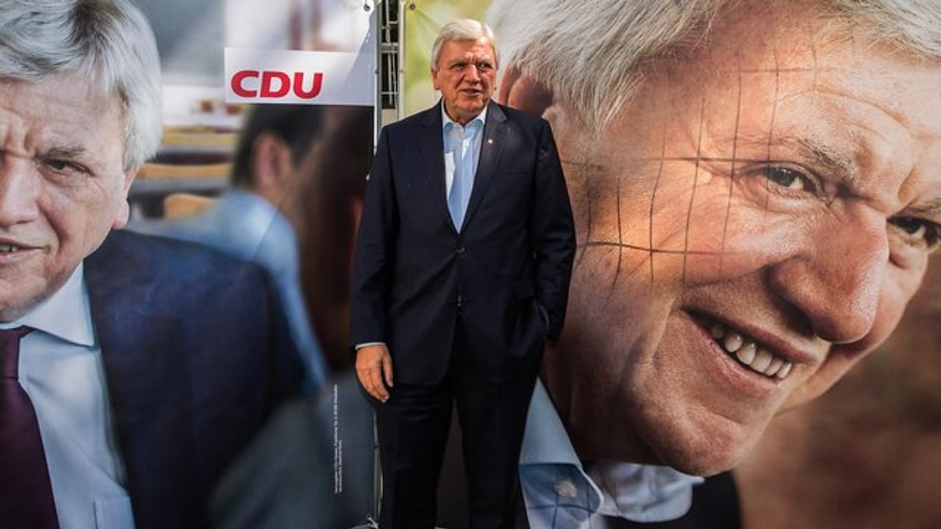 Hessens Ministerpräsident Volker Bouffier posiert in Wiesbaden zwischen den Wahlplakaten.